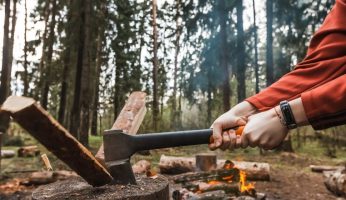 Female strong hands chop firewood with axe for bonfire